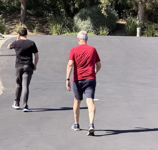 Sam and J Brad walking outdoors, highlighting the lifestyle and daily advocacy of the nonspeaking community.